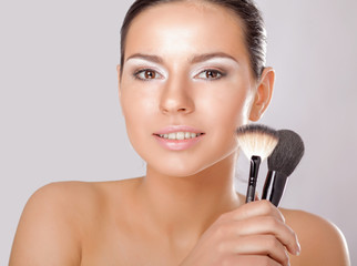 Portrait of attractive young adult woman applying blusher.
