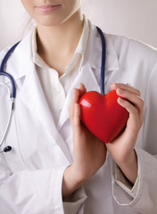 Female doctor with stethoscope holding heart