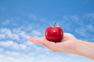 hand with an apple isolated on sky