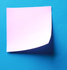 Pink paper note on blue background isolated.