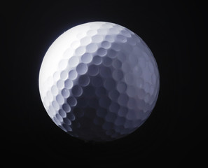 A close-up of a golf ball over dark background.