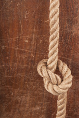 Fototapeta na wymiar Rope with Reef Knot on Wood Texture Background
