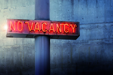 Glowing retro neon 'no vacancy' sign against blue wall - 61221039