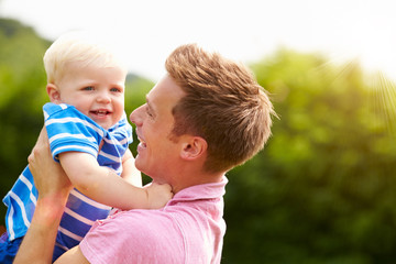 Father Hugging Young Son In Garden