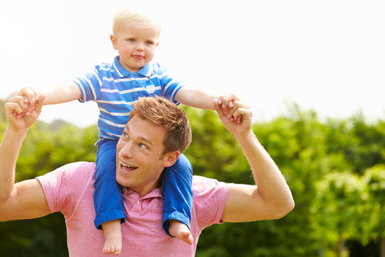 Father Giving Young Son Ride On His Shoulders In Garden