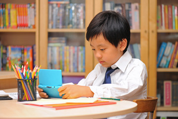 Schoolboy distracted by game machine during homework time