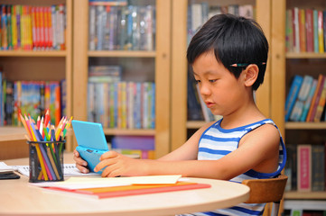 Schoolboy distracted by game machine during homework time