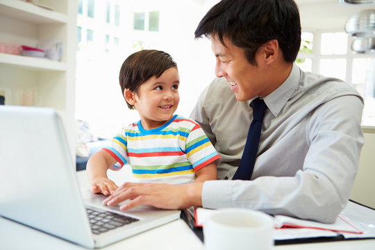 Busy Father Working From Home With Son