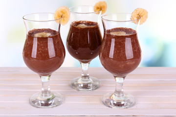 Cocktails with banana and chocolate on table on light