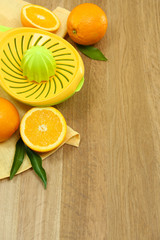 Citrus press and oranges on wooden background