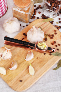 Composition with garlic press, fresh garlic and glass jars with
