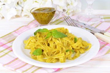 Delicious pasta with pesto on plate on table close-up