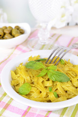 Delicious pasta with pesto on plate on table on light