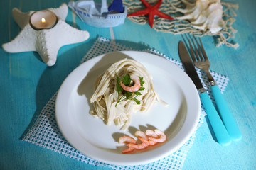 Pasta with shrimps on white plate, on wooden background