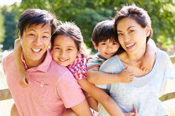 Portrait Of Asian Family Enjoying Walk In Summer Countryside