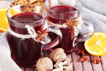 Mulled wine with lemon and nuts on table on fabric background