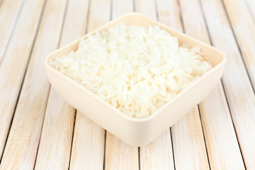 Cooked rice in bowl on wooden background