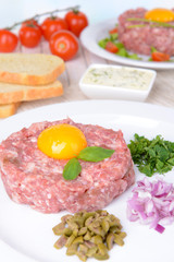 Delicious steak tartare with yolk on plate on table close-up
