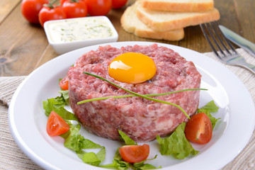 Delicious steak tartare with yolk on plate on table close-up