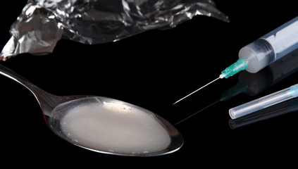 Heroin in spoon on black background