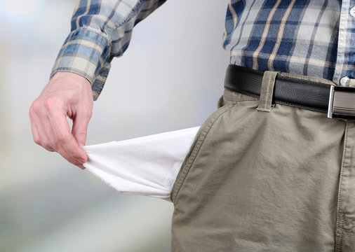 Man showing his empty pocket on bright background