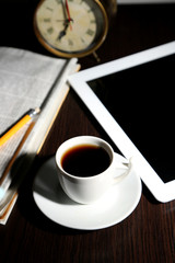 Fototapeta na wymiar Tablet, newspaper, cup of coffee and alarm clock on wooden