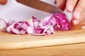 Female hands cutting bulb onion, close up