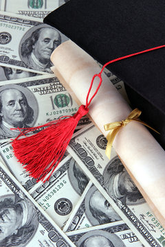 Graduation hat and scroll on money background