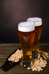 Glasses of beer with snack on table on dark background