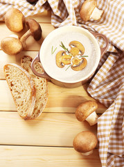 Mushroom soup in pot, on napkin,  on wooden background