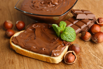 Bread with sweet chocolate hazelnut spread on wooden background