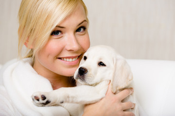 Woman in white sweater holds a cute Labrador puppy - 61231000