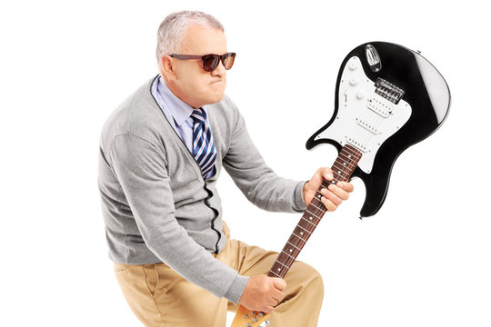 Angry Mature Man Breaking An Electric Guitar