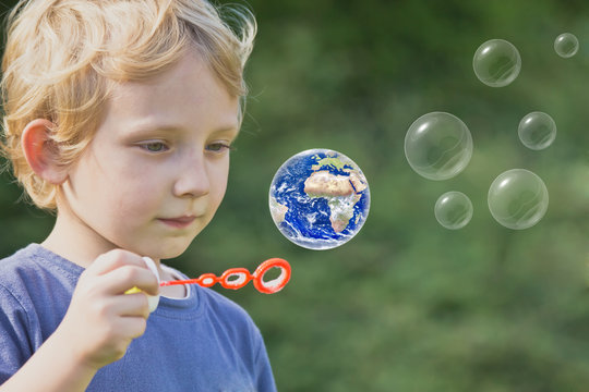 Caucasian blond boy is playing with soap bubbles