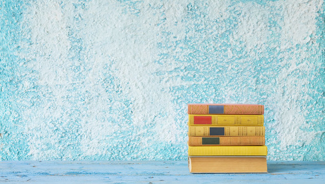 stack of books on blue wall background, free copy space