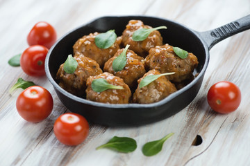 Frying pan with meatballs over wooden background