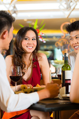 Waiter serving Chinese couple red wine in fancy restaurant