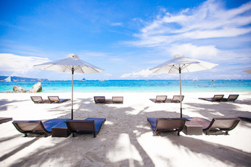 Fototapeta na wymiar White umbrella and chairs at beach background the blue sea