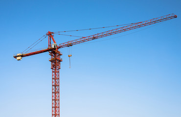 Red tower crane on blue sky background.