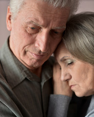 Sad elder couple on brown background