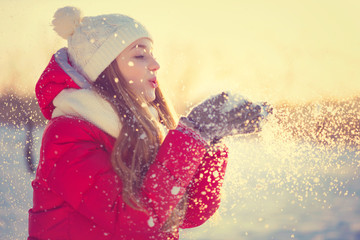 Beauty Winter Girl Blowing Snow in frosty winter Park. Outdoors