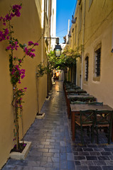 Fototapeta na wymiar Restaurant in shade at street of old city and harbor, Crete