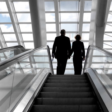 Man and woman on an escalator.