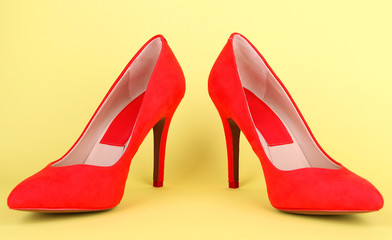 Beautiful red female shoes, on yellow background
