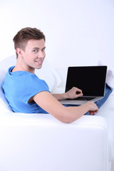 Guy sitting on sofa with laptop on white background
