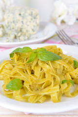 Delicious pasta with pesto on plate on table on light