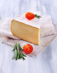 Tasty Camembert cheese with rosemary and tomato, on wooden