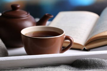 Cup of hot tea with teapot and book