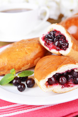Fresh baked pasties with currant on plate on table close-up