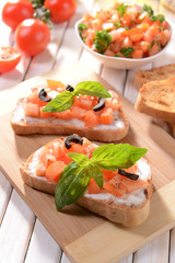 Delicious bruschetta with tomatoes on cutting board close-up